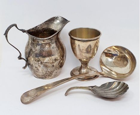 A 19th century silver caddy spoon, crested, with a shell bowl, a silver ladle, a silver cream jug and a silver egg cup, 5.3 o