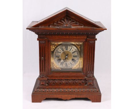 Oak cased mantle clock of architectural form with brass dial, Roman numeral chapter ring, striking on a coil, the back plate 