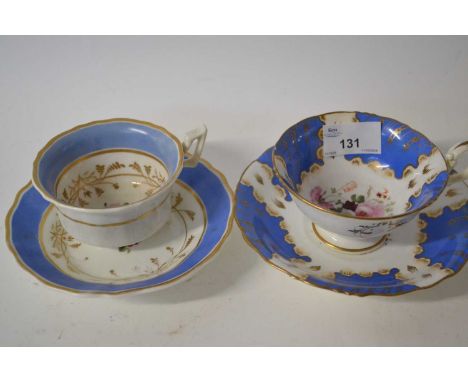 Two early 19th Century English porcelain cups and saucers with painted floral designs within blue borders