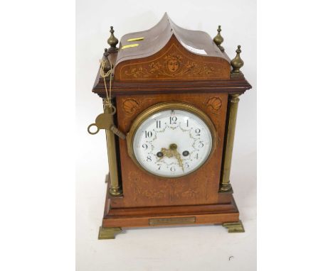 A late 19th Century mantel clock with unsigned porcelain dial set in an architectural inlaid case with brass pillared support