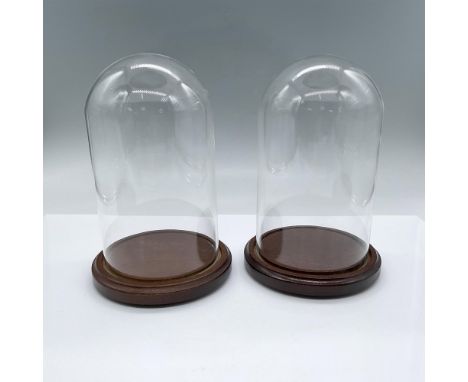 Two glass domes fitted into light mahogany stained wooden bases. One measures 7.5"H x 5"dia., the slightly darker one measure