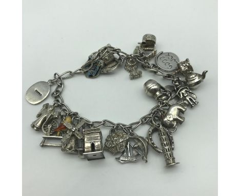 A Silver charm bracelet with 26 Silver charms. Includes 4 silver and enamel charms. 
