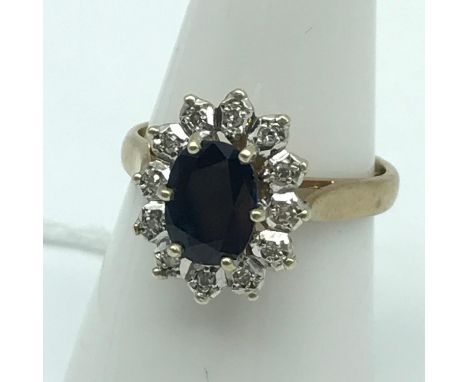 A Ladies 9ct gold ring set with a single large Sapphire and 12 round cut diamonds. 0.06ct of diamonds. Ring size N and weighs