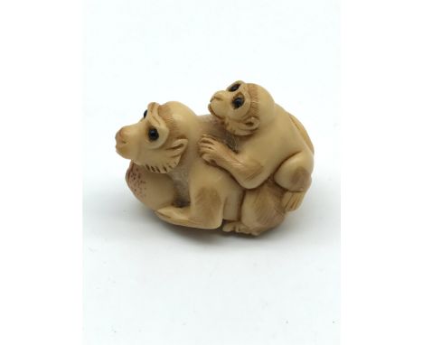 A Japanese hand carved Tagua nut netsuke figure of a monkey with baby, Both have black bead eyes. Signed by the artist. Measu
