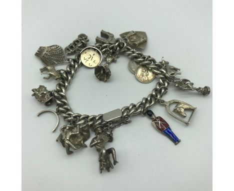 A Heavy silver charm bracelet with 17 charms, Includes musician, Silver and enamel guard, Motorbike and flamenco dancer. 