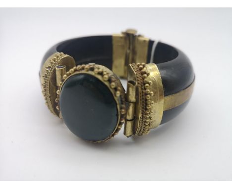 Antique ornate slave bangle, made from horn, gilt brass and showing a large dark green stone to the centre. 