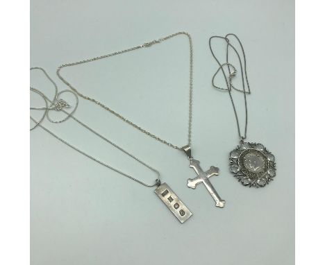 A Lot of three silver necklaces with silver pendants which include Birmingham silver ingot, Silver cross and ornate encased G