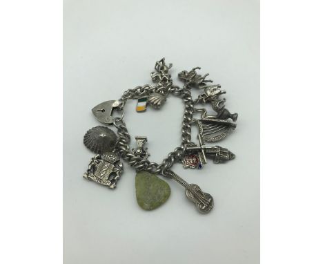 A Heavy silver charm bracelet with 14 charms includes figures on horse back, Irish silver harp and Irish silver and enamel fl