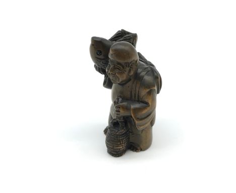 A Japanese hand carved netsuke figure, of an old gentleman carrying a Koi carp on his shoulder. Carp has black bead eyes and 