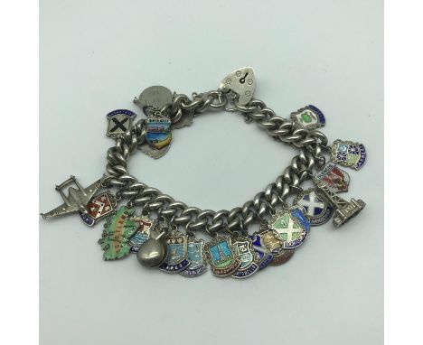 A Heavy silver charm bracelet with silver and enamel charms. 24 charms in total. 