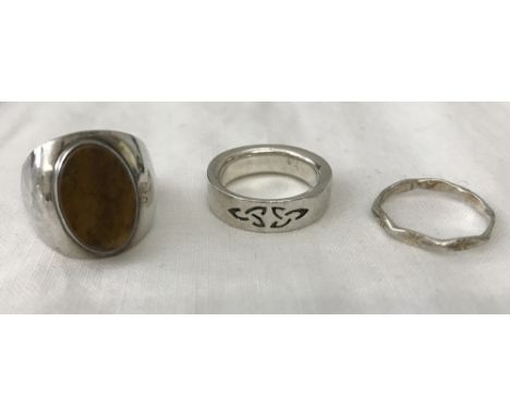 3 silver dress rings. A Celtic design band ring. A thin decorative band and a oval tigers eye set ring. Sizes k 1/2, J1/2 and