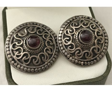 A pair of large round silver earrings set with central cabochon garnets. Scroll and beadline decoration to front. Stamped 925