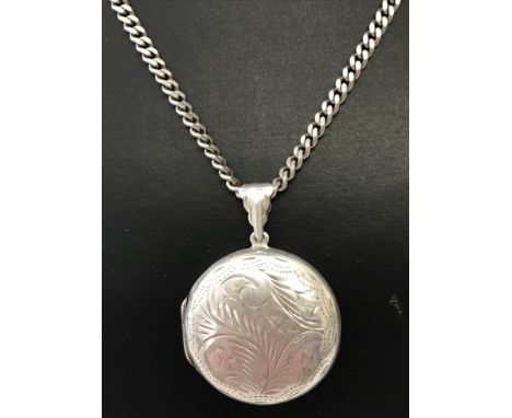 A round silver locket with engraved detail to front and back on a 16inch curb chain. Both locket and chain stamped 925. Total