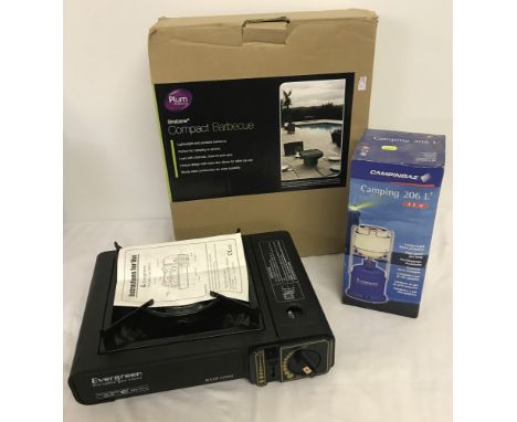 A boxed Compact barbecue together with a portable gas stove and a boxed camping lamp.  
