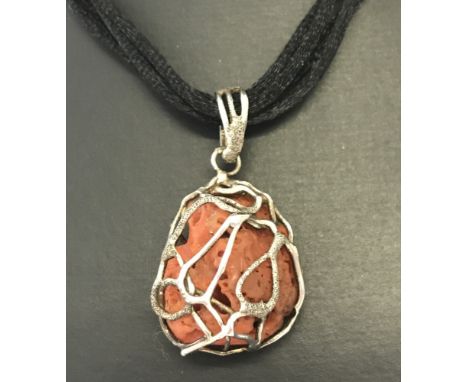 A contemporary design pendant made from natural coral decorated with silver. On a black cord thong. 