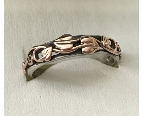 A 925 silver and welsh gold clogau band ring. Traditional decoration to top half of band. Size R.