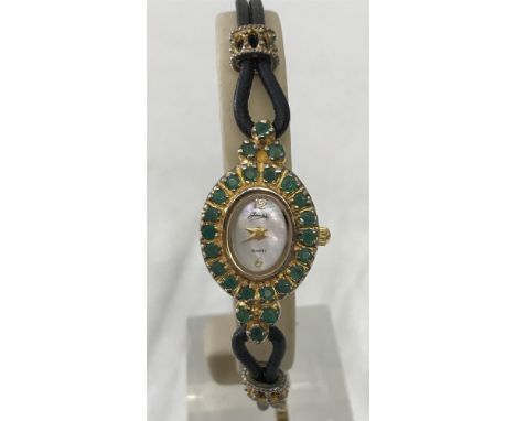 A ladies 925 silver gilt wristwatch set with emeralds by Gems. Mother of pearl face with 12 and 6 hour markers. Seconds hand.