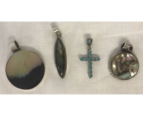 4 silver and white metal pendants. A circular shell pendant, a cross set with blue stones, a circular paua shell and garnet p