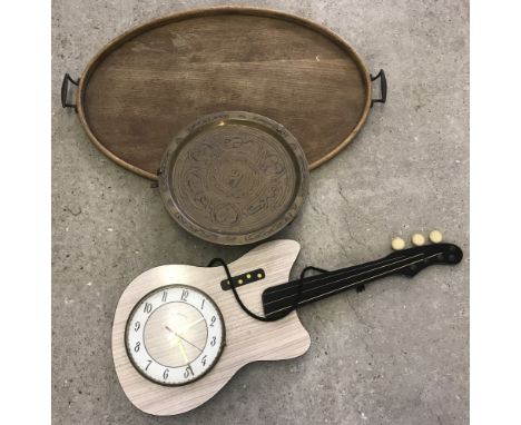 A vintage oval shaped 2 handled wooden tray together with an oriental brass tray and a 1960's guitar shaped wall hanging cloc