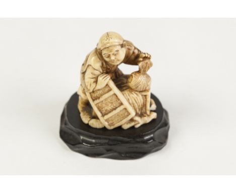 A JAPANESE MEIJI PERIOD CARVED IVORY NETSUKE in the form of a peasant at work, signed (small loss to the base) 