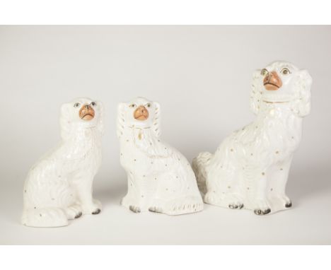 THREE NINETEENTH CENTURY STAFFORDSHIRE POTTERY MANTLE DOGS, each of typical form with gilt splashed coat, comprising: A PAIR,