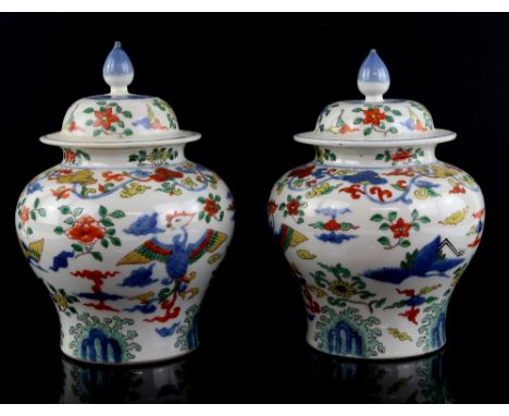 A pair of wucai style oviform vases; each one with a domed cover and knop finial; both decorated with cranes and phoenix and 