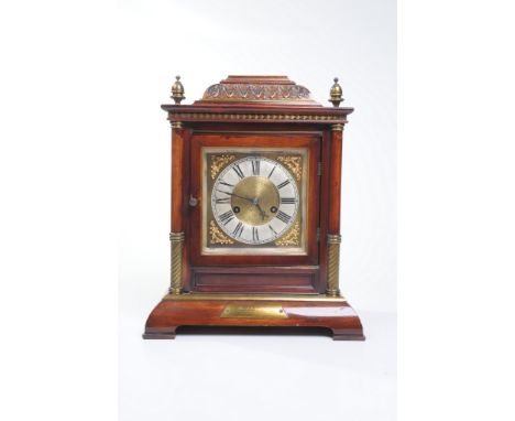 A simulated walnut cased mantle clock early 20th Century
With a 13cm silvered dial with Roman numerals, leafy spandrels the t