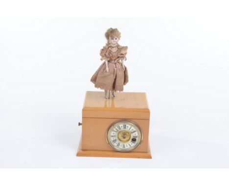 An unusual musical clock surmounted with a bisque head dancing doll, late 19th Century
With a 6cm dial, Roman numerals, pierc