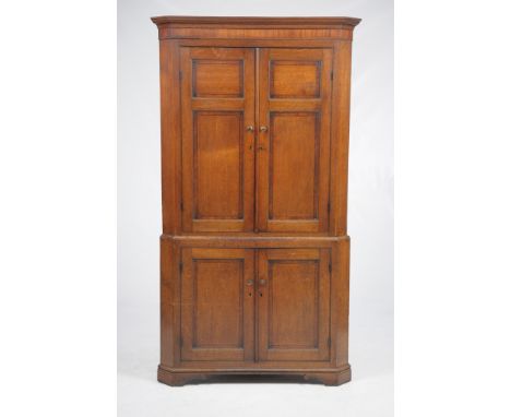 An early 19th Century oak and mahogany crossbanded free standing corner wall cupboard
With a cavetto cornice above a plain fr