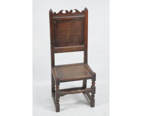 A 17th Century oak back stool
With pyramidal  finials, a shaped cresting above a panelled back, panelled seat raised upon squ