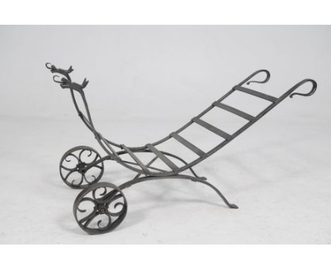 A cast iron log carrier
Of concave ladder form with serpent terminals and scroll handles raised upon solid iron wheel 100cm x