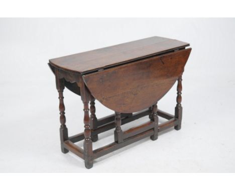 An oval oak gateleg dining table, 18th Century
The oval plank top raised upon square headed ring turned baluster supports ext