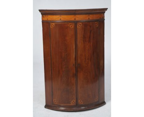 An early 19th Century mahogany and satinwood inlaid hanging bow front corner cupboard
With a cavetto cornice with a satinwood