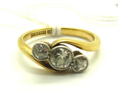 A Three Stone Diamond Crossover Ring, the graduated brilliant cut diamonds circular collet set to centre, between crossover s
