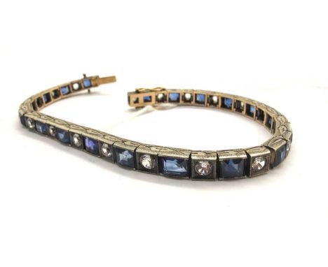 An Art Deco Stone Set Line Bracelet, the alternately emerald and round cut stones, graduated collet set within a decorative t