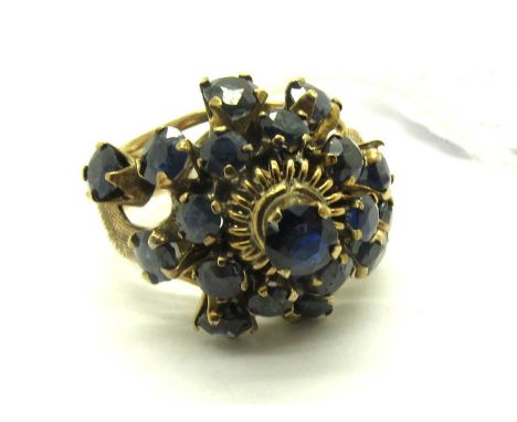 A Sapphire Set Abstract Cluster Ring, the graduated stones to four claw set throughout, the cathedral set centre stone with t