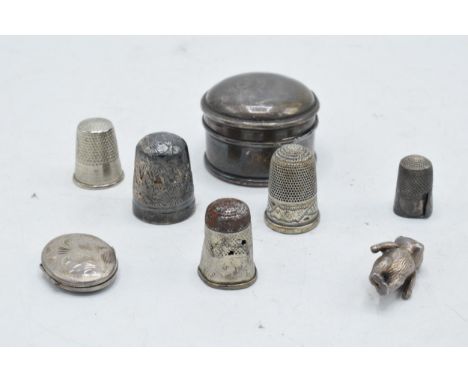 A collection of silver items to include a round pillbox, a locket, a silver thimble and other examples together with a charmi