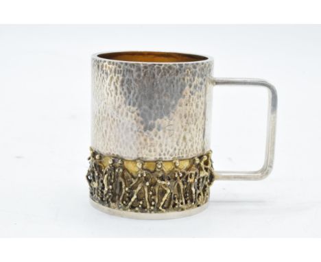 Stuart Devlin: A silver and silver gilt tankard / cup with figural decoration to the bottom half of the main body. London 197