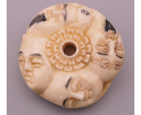 A bone carved netsuke depicting faces.  4 cm diameter. 