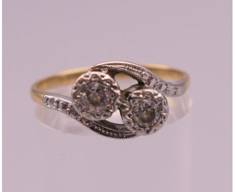 An 18 ct gold two stone diamond crossover ring. Ring size N/O. 2.7 grammes total weight.