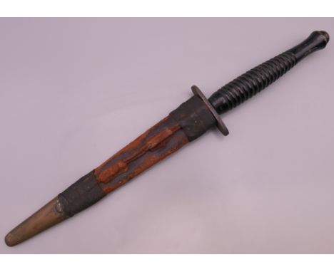 An unmarked Fairbairn Sykes Commando dagger in sheath. 30 cm long excluding scabbard, 32 cm long including scabbard.