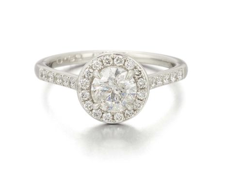 A PLATINUM DIAMOND CLUSTER RING a round brilliant-cut diamond within a border of smaller diamonds, to diamond-set shoulders a