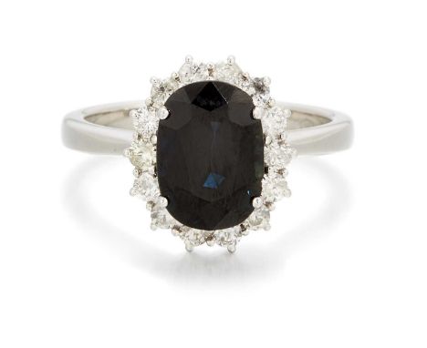 AN 18 CARAT WHITE GOLD SAPPHIRE AND DIAMOND CLUSTER RING a cushion-cut sapphire within a border of round brilliant-cut diamon