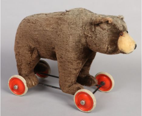 A rare mid 20th century Steiff bear on wheels. Straw frilled, with button to ear and with growler, 58cm long. 