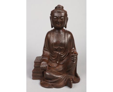 A 19th century Chinese cast iron statue of Buddha. Modelled in a seated pose next to a stack of books. Qianlong seal mark to 