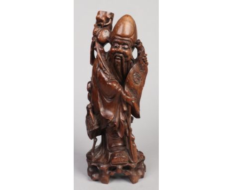 An early 20th century Chinese carved hardwood figural tablelamp base formed as a sage. Stood holding a scroll and with a cran