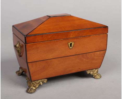 A Regency satinwood tea caddy. With ebony stringing, gilt metal loop handles and paw feet, 20cm wide. Some loss to the string