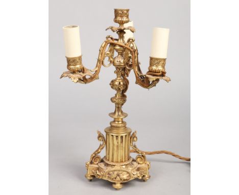 A French gilt bronze three branch tablelamp. With leaf moulded sconces and raised on a column plinth adorned with birds and r