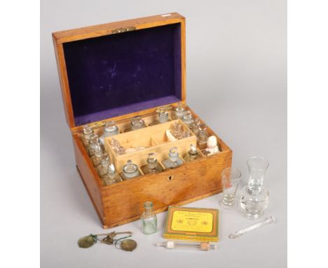 A Victorian light oak fitted medicine box. Housing an array of glass bottles, some with labels, glass measures, mortar and pe