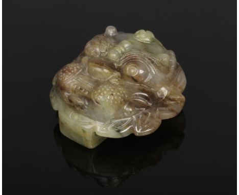 A Chinese carved jade buckle. Formed as the mask of a mythical beast. Green with brown and lilac suffusions, 5cm. Good condit